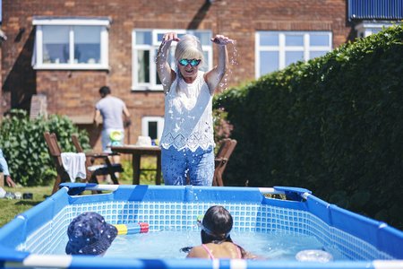 Seniorin mit ihren Enkeln am Pool