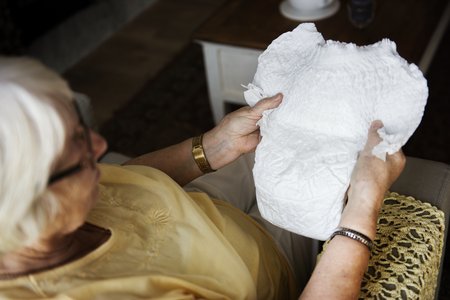 Seniorin hält Inkontinenzhose in der Hand