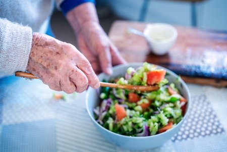 Eine ausgewogene Ernährung im Alter bedeutet nicht nur Verzicht und Fasten. Viele gesunde Leckereien sind ein echter Gaumenschmauß. Ältere Menschen bereiten einen Salat zu