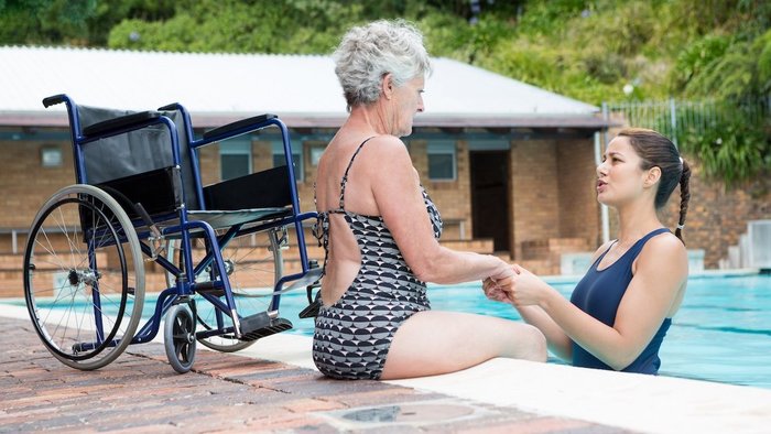 Seniorin am Beckenrand im Schwimmbad