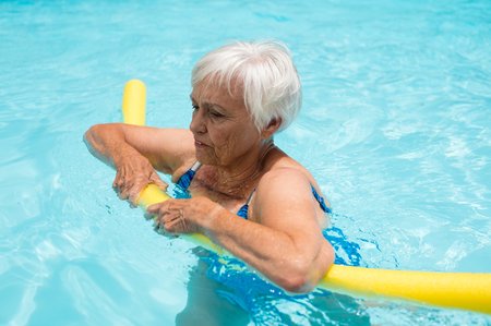 Seniorin mit Schwimmnudel im Wasser