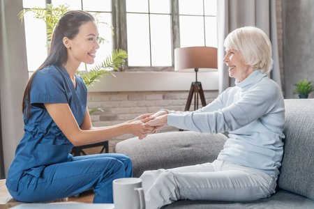 Eine Pflegerin hält die Hand einer Seniorin